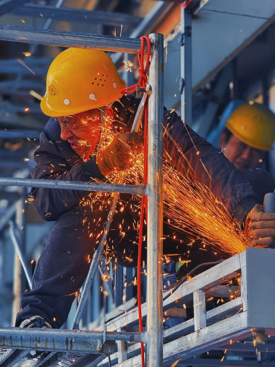 A man in a hard hat grinding metal with a grinder